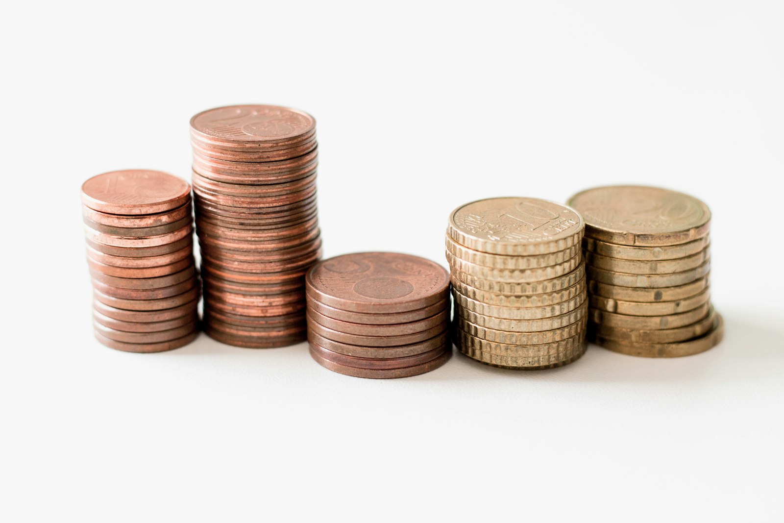 Five stacks of small-denomination coins of varying heights on a white background.