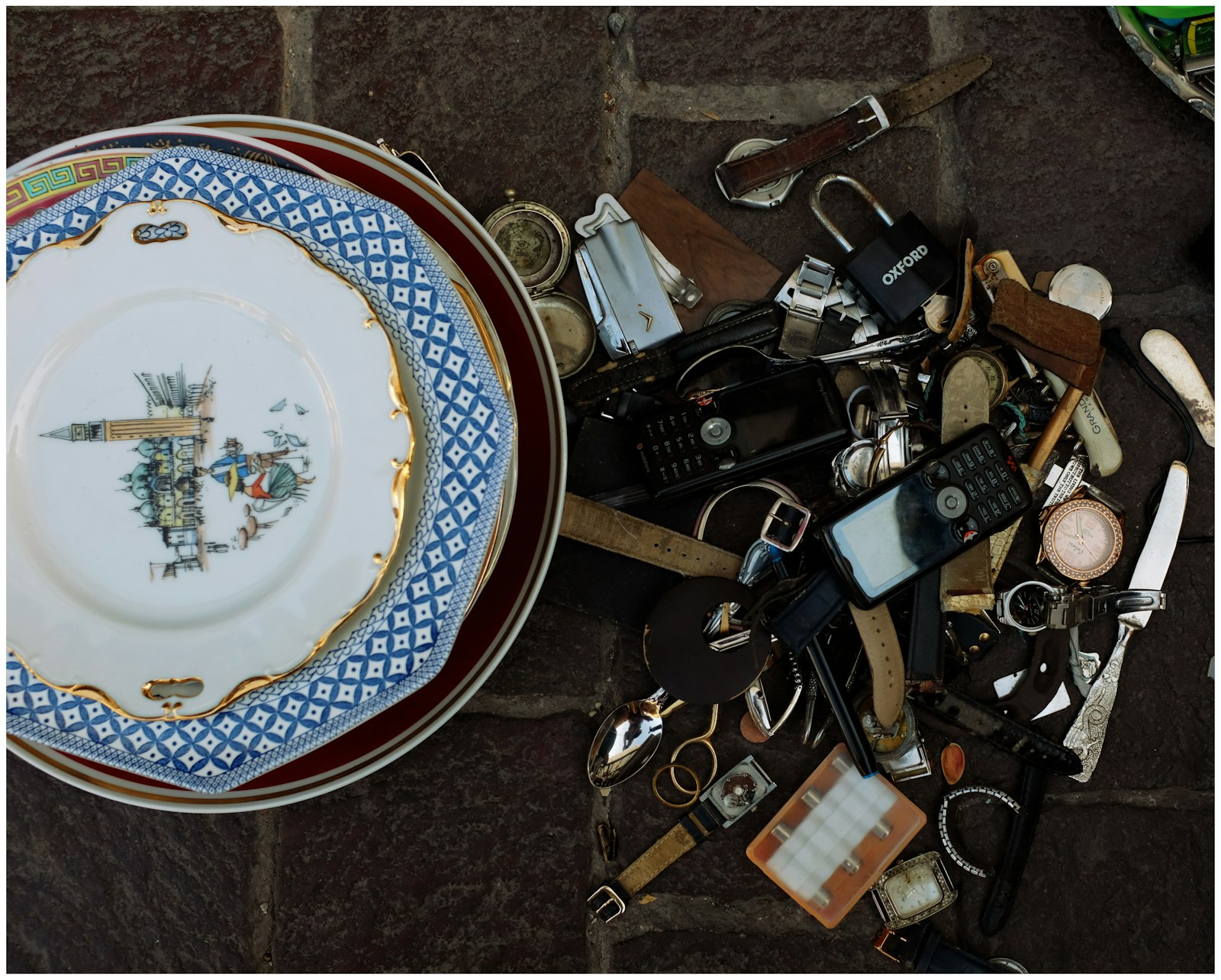 A market stall: a stack of decorative plates next to a pile of assorted objects.