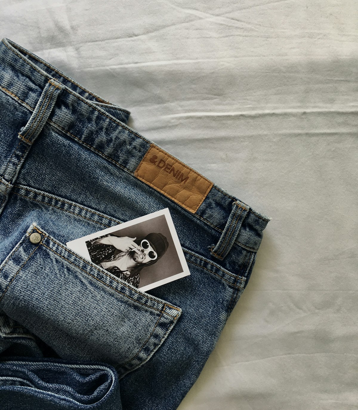 A pair of blue jeans laid flat on a white background — a product photo.
